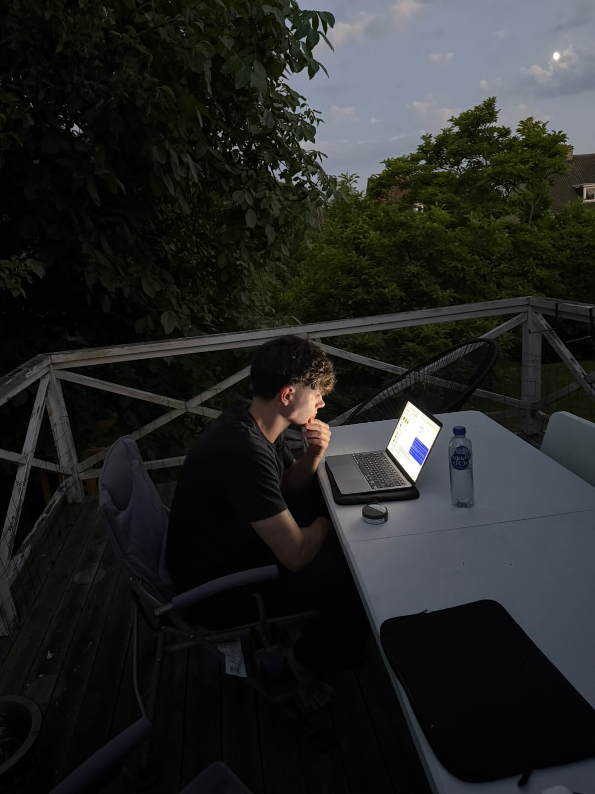 Elliot working on a laptop outdoors in the evening